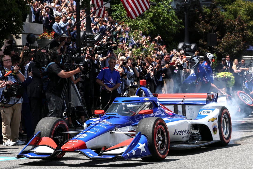 Visitors watch a Freedom 250 Grand Prix showcase on West Executive Avenue in Washington on July 13, 2026. The IndyCar Freedom 250 Grand Prix car race is scheduled for Aug. 22–23 on the National Mall as part of America's 250th anniversary celebrations. (Win McNamee/Getty Images)