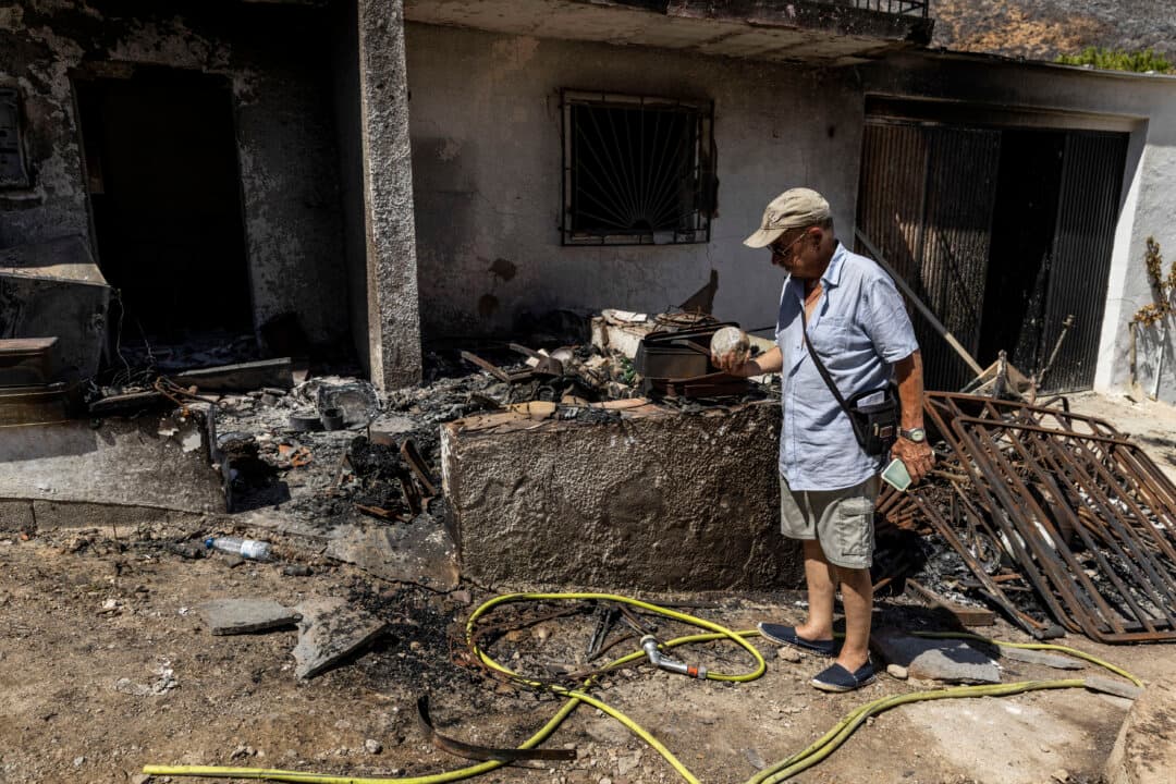 A man checks a scorched glass ball next to his burnt house following the Los Gallardos wildfire in Almería, Spain, on July 13, 2026. The catastrophic wildfire has claimed 12 lives and burned close to 7,000 hectares of land, forcing 1,500 people to evacuate. (Pablo Blazquez Dominguez/Getty Images)