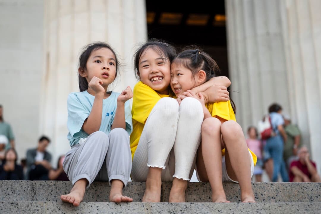 Young girls smile as Falun Dafa practitioners hold a candlelight in Washington on July 23, 2026. (Madalina Kilroy/The Epoch Times)