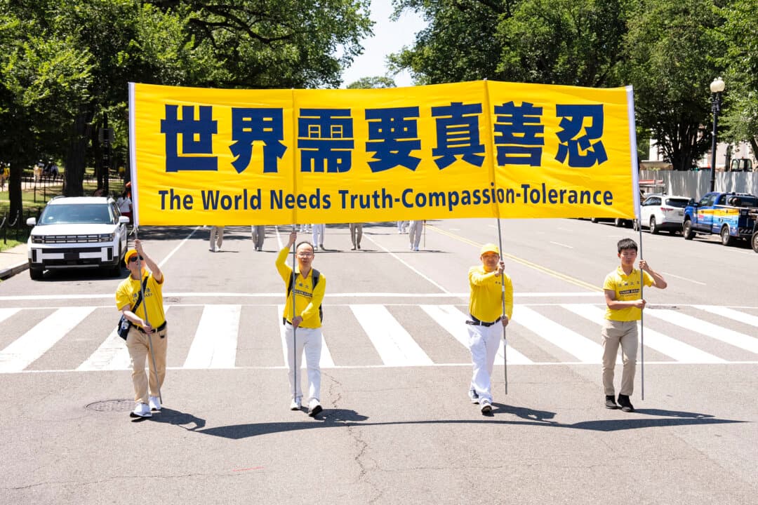 Falun Dafa practitioners hold a banner that reads “The World Needs Truth-Compassion-Tolerance” in Washington on July 23, 2026. (Larry Dye/The Epoch Times)