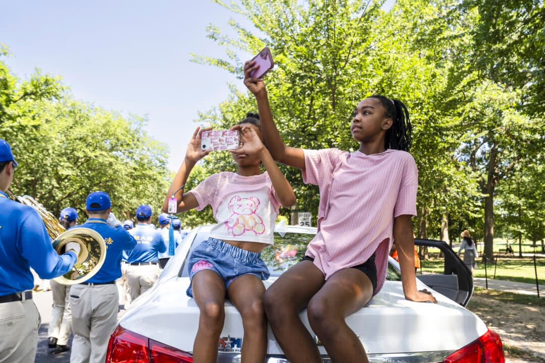 Passersby watch the Tian Guo Marching Band in Washington on July 23, 2025. (Madalina Kilroy/The Epoch Times)