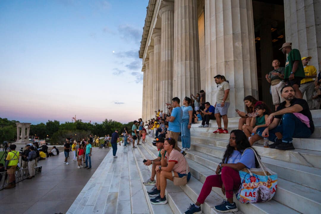People look on as Falun Dafa practitioners hold a candlelight vigil in Washington on July 23, 2025. (Samira Bouaou/The Epoch Times)
