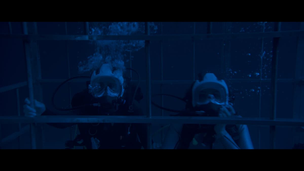 Tatiana (Laura Marano) and Kayle (Christina Ochoa) trapped in a shark cage, in “Above and Below.” (Aura Entertainment)