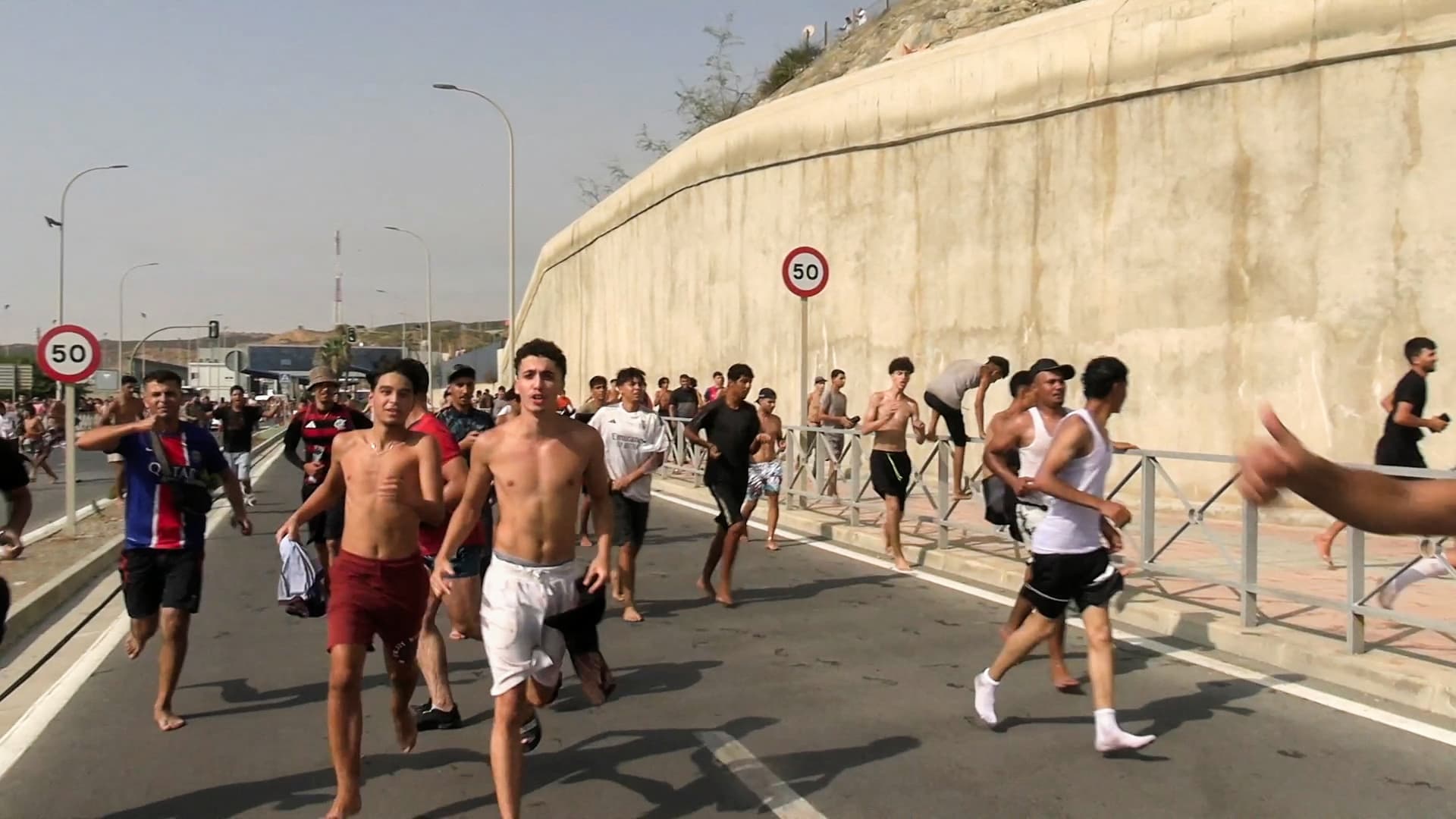 Immigrants run and cheer as they cross on foot into the Spanish North African enclave of Ceuta from Morocco, after swimming over from the Moroccan side and overwhelming police at the city's breakwater, according to Spain's Guardia Civil, in Ceuta, Spain, July 30, 2026, in this screenshot obtained from a handout video. (Faro TV via Reuters)