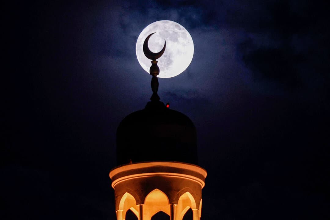 The "buck" full moon rises behind the spiral-shaped minaret of the Abdulla Bin Zaid al-Mahmud Islamic Cultural Center, also known as the Fanar Mosque, in Doha, Qatar, on July 29, 2026. (Karim Jaafar/AFP via Getty Images)