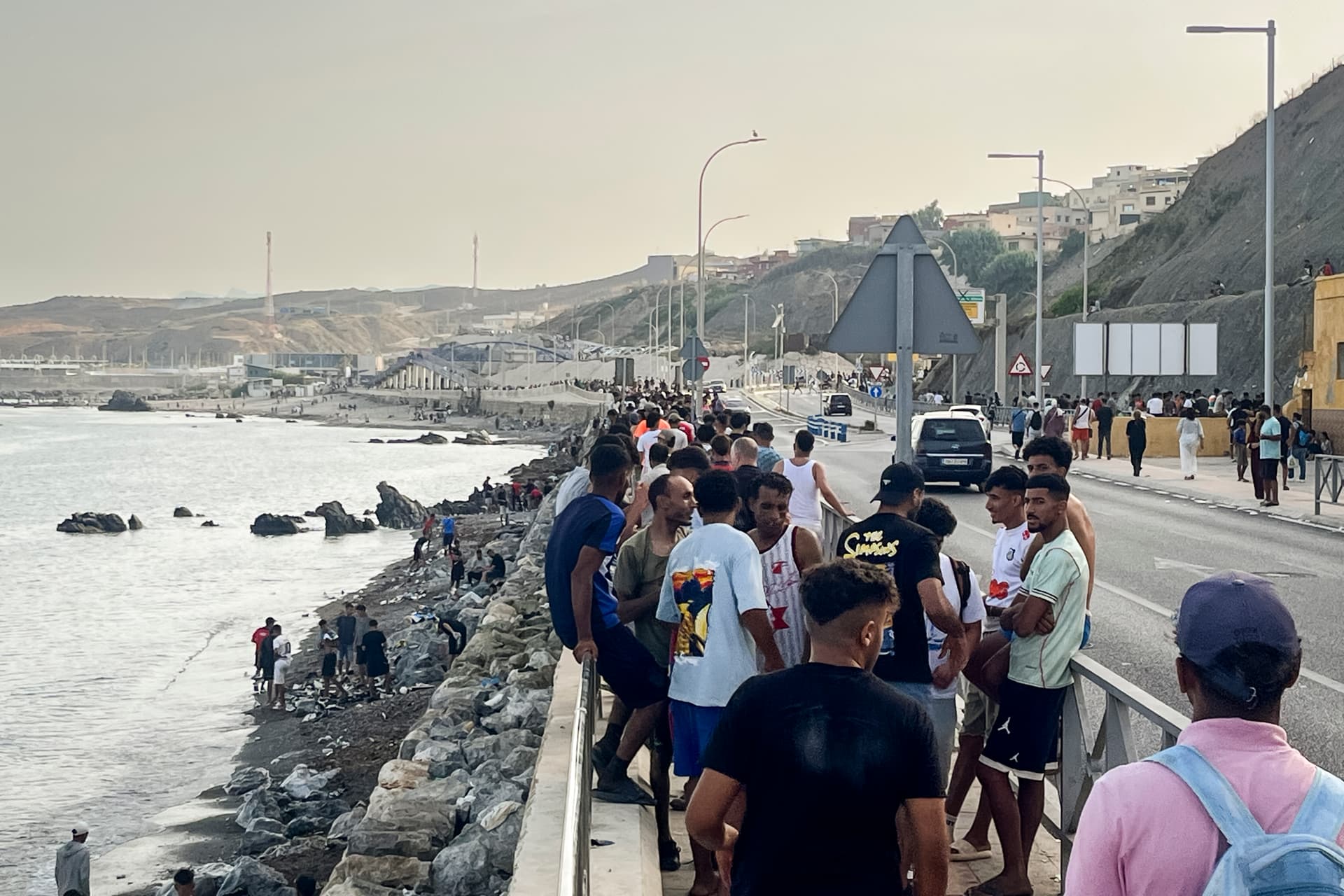 Crowds of young Moroccan migrants gather along the coastal road near Avenida Martínez Catena in the Spanish territory of Ceuta, in Spain, on July 31, 2026, after swimming across from Morocco. (Etienne Fauchaire/The Epoch Times)