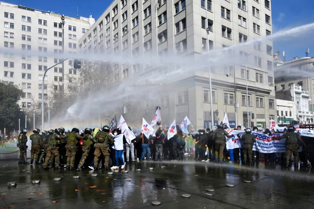Healthcare workers clash with riot police in front of La Moneda presidential palace during a protest against cuts to Chile's public healthcare system in Santiago, Chile, on Aug. 6, 2026. (Rodrigo Arangua/AFP via Getty Images)
