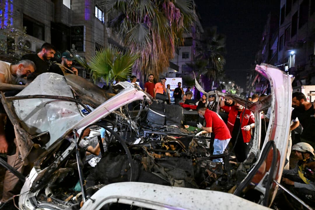Rescuers and onlookers inspect the wreckage of a minibus at the site of a blast near Damascus, Syria, on Aug. 6, 2026. A bomb planted on the minibus exploded in the town of Jaramana, state television reported, citing an official source. (Louai Beshara/AFP via Getty Images)
