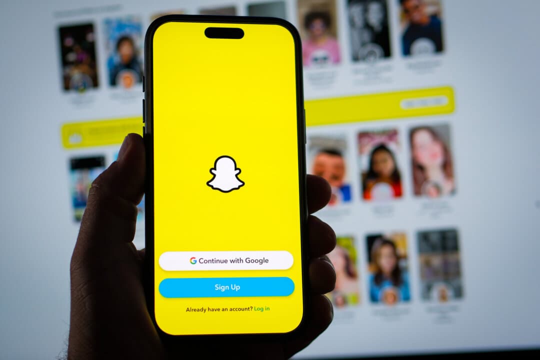 A person holds a phone displaying the Snapchat app, in this photo illustration on Aug. 11, 2026. Snapchat says about 90 percent of 13- to 24-year-olds worldwide use the app, which is known for ephemeral messaging, augmented reality filters, and live location sharing. (Oleksii Pydsosonnii/The Epoch Times)