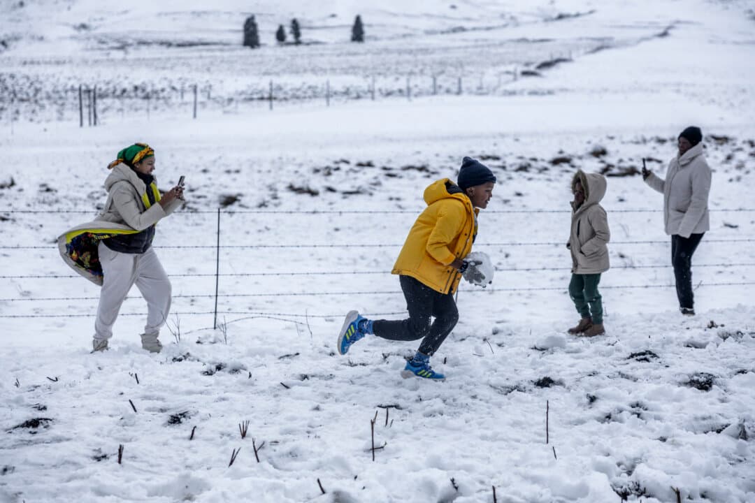 A family gathers to play in snow on Nottingham Road near Pietermaritzburg, South Africa, on Aug. 10, 2026. Parts of the South African province hit with late snow, just ahead of the southern hemisphere spring. (Rajesh Jantilal/AFP via Getty Images)