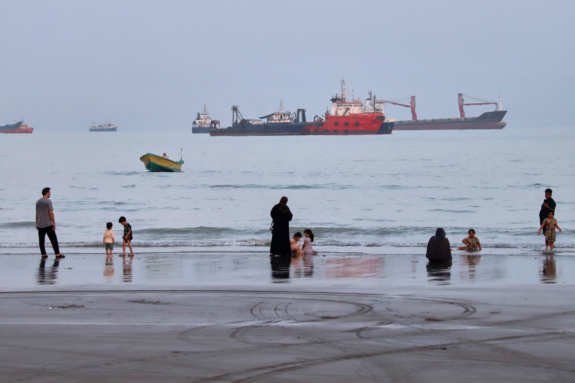 People spend time at a beach as commercial vessels are anchored in the Strait of Hormuz off Bandar Abbas, Iran, on Aug. 5, 2026. (Amirhosein Khorgooi/ISNA via AP)