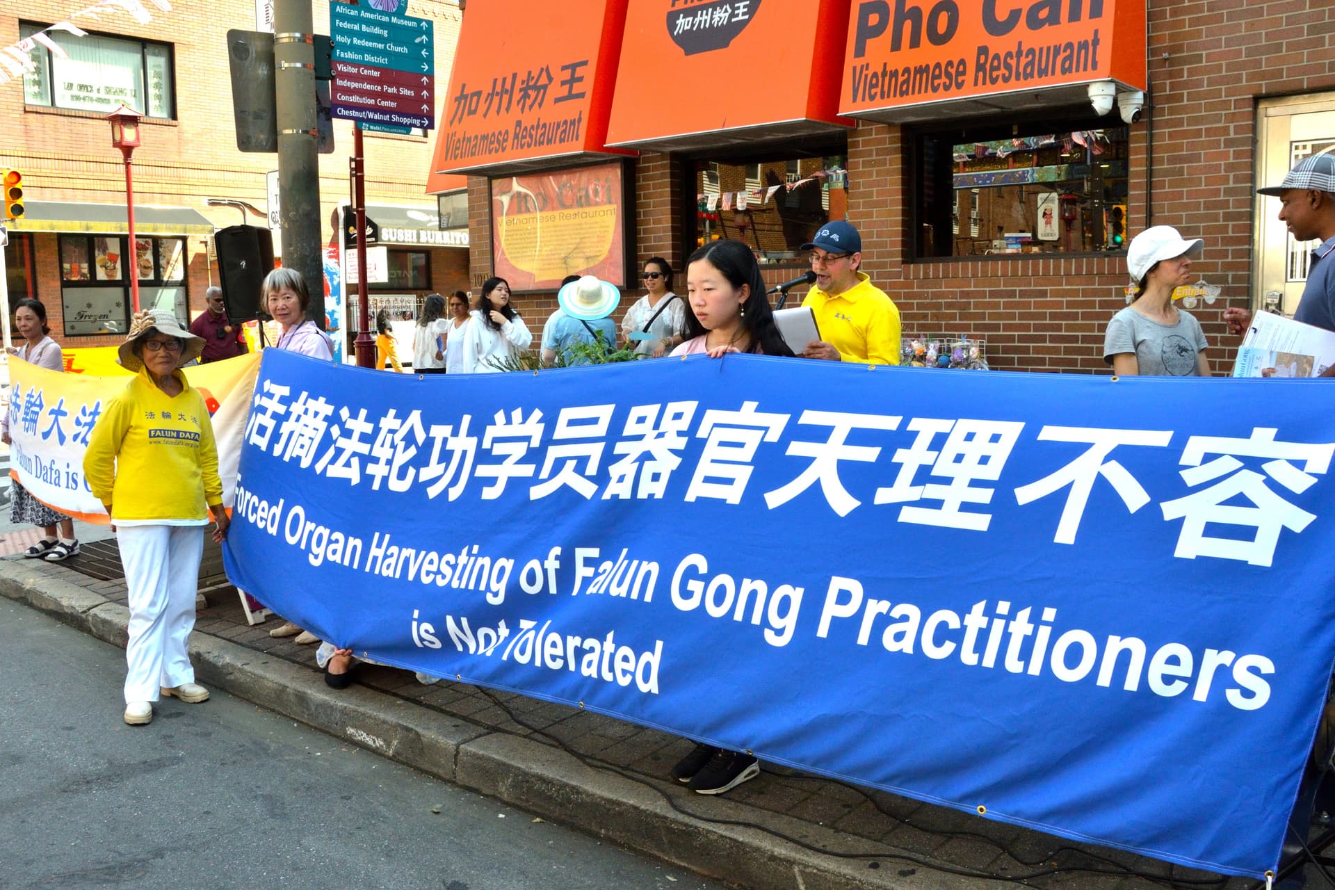 Tian Zhongfeng, in front of the banner, at the rally in Philadelphia on Aug. 15, 2026. (Frank Liang/The Epoch Times)