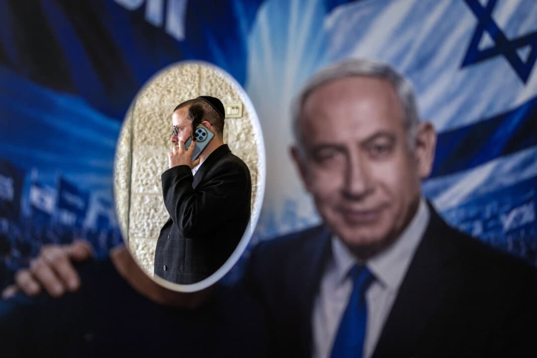 A member of the Likud party is pictured through a poster featuring Israeli Prime Minister Benjamin Netanyahu at a polling station during the party's primary elections in Jerusalem on Aug. 17, 2026. Israel will hold national elections on Oct. 27. (Ilia Yefimovich/AFP via Getty Images)