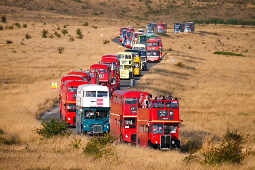 Buses leave the abandoned village of Imber on the Ministry of Defense training area on England's Salisbury Plain on Aug. 15, 2026. The annual Imberbus charity service operates for one day, taking passengers along restricted military roads to the abandoned village and raising money for local charities and the Royal British Legion Poppy Day Appeal. (Finnbarr Webster/Getty Images)