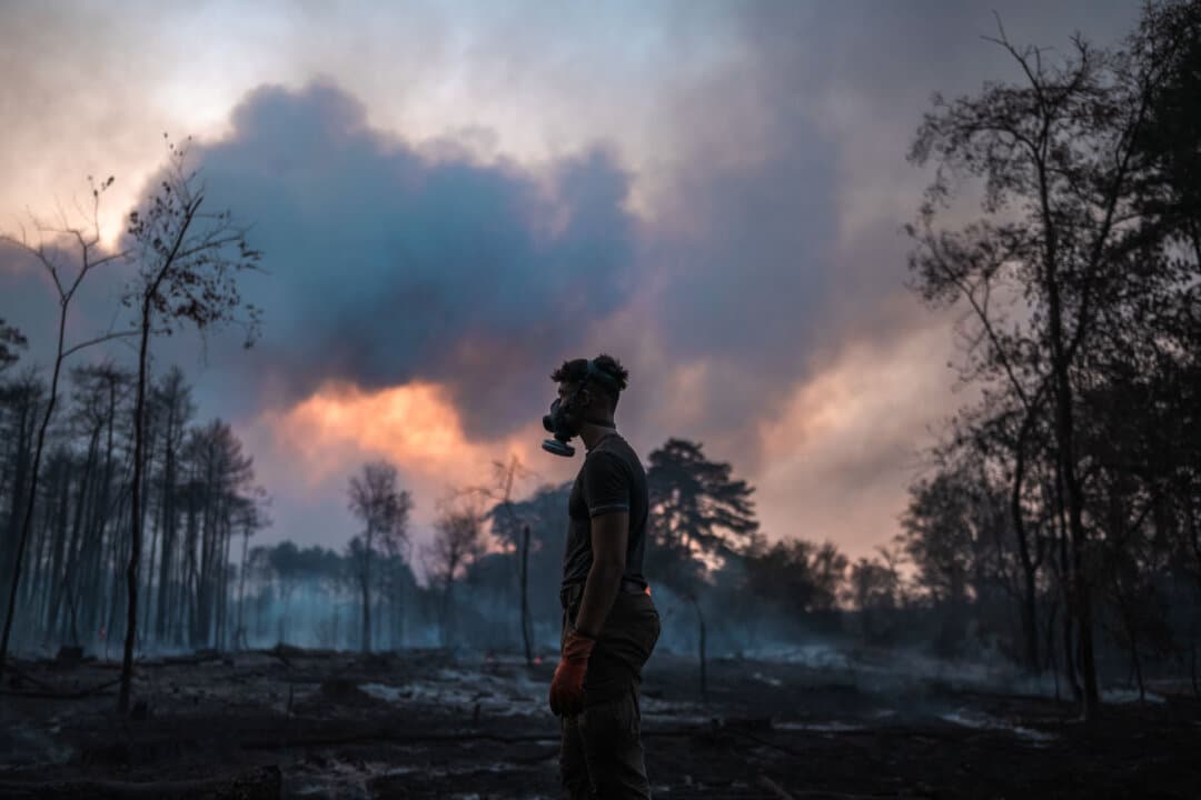 A local resident wearing a mask stands in front of a scorched forest during a wildfire in Deliblatska Pescara near Grebenac, Serbia, on Aug. 20, 2026. Crews were battling wildfires across the Balkans as high temperatures and drought conditions continued to fuel blazes in several countries. (Uros Arsic/AFP via Getty Images)