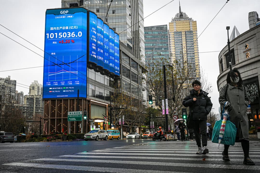 Pedestrians pass a screen showing figures of China's gross domestic product on a street in Shanghai on Jan. 19, 2026. China's economy grew at one of the slowest rates in decades last year. (Jade Gao/AFP via Getty Images)