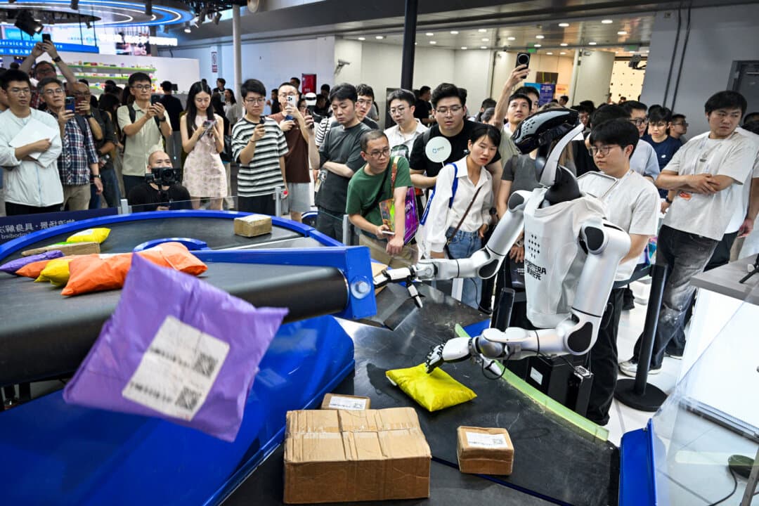 A humanoid robot by Robotera works with packages during the World Artificial Intelligence Conference in Shanghai on July 18, 2026. China is investing heavily in AI despite an overall investment decline. (Hector Retamal/AFP via Getty Images)