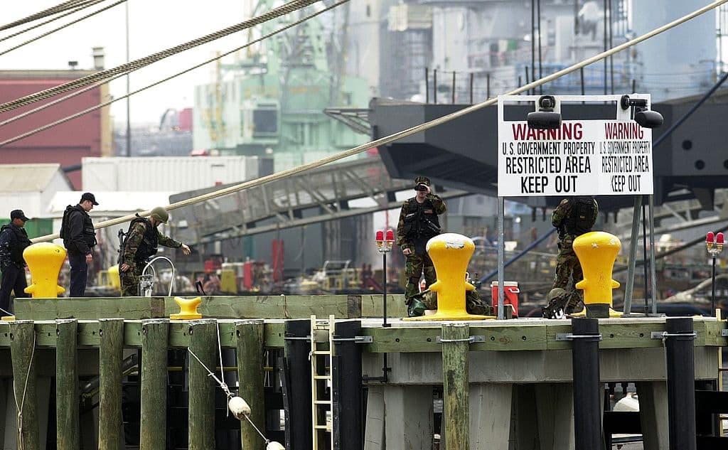 U.S. Marines watch passing boats along the Elizabeth River as they guard the piers of the Norfolk Naval Shipyard in Portsmouth, Virginia, on April 5, 2003. (Liza Mizelle/Getty Images)
