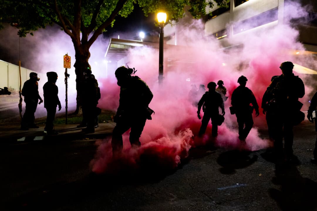 Federal officers deploy smoke grenades to deter protestors in front of Immigration and Customs Enforcement offices in Portland, Ore., on Oct. 5, 2025. (John Fredricks/The Epoch Times)