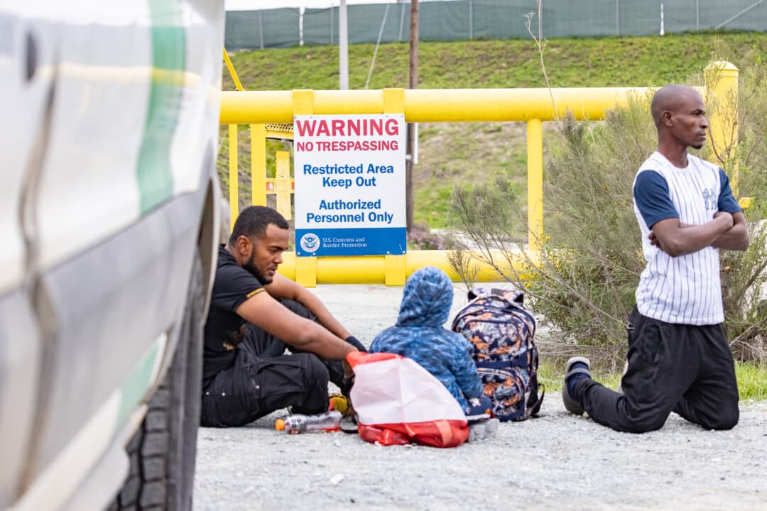 Illegal immigrants await processing by Border Patrol agents in Otay Mesa, Calif., on Feb. 29, 2024. (John Fredricks/The Epoch Times)