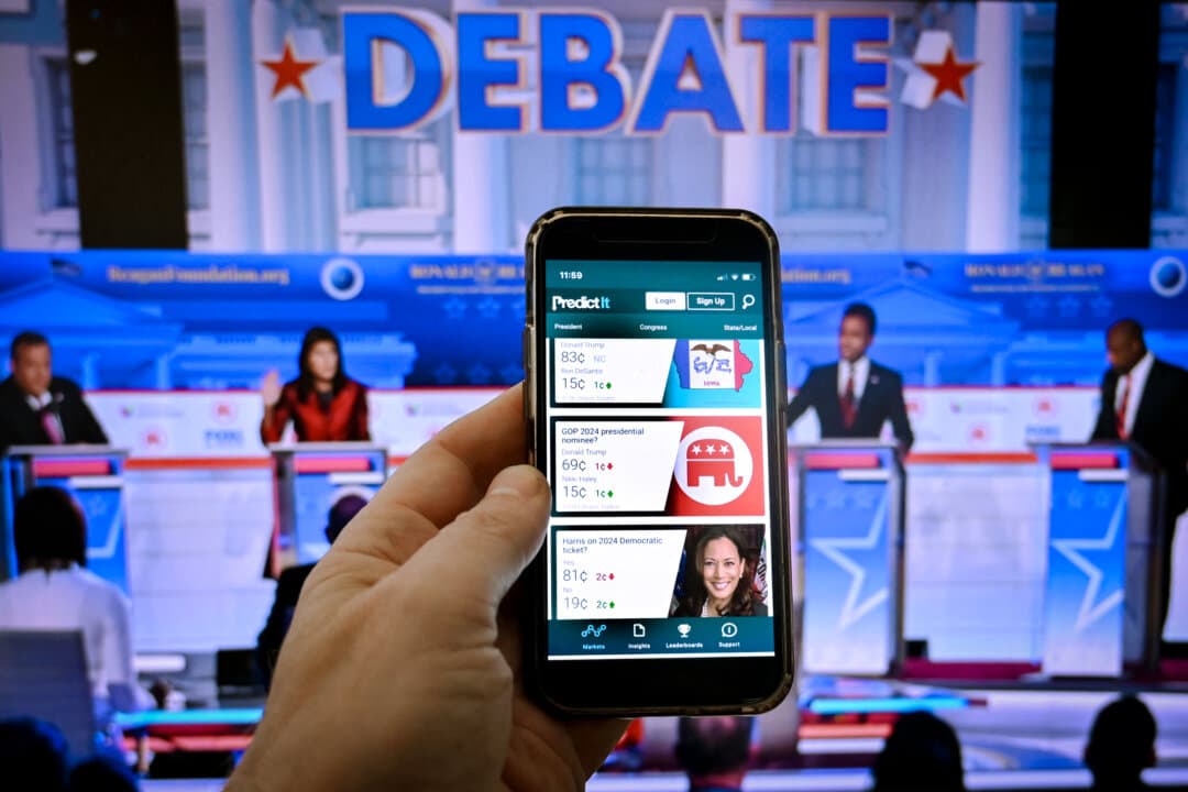 This photo illustration taken in Washington on Nov. 1, 2023, shows a phone screen displaying online prediction market PredictIt with a picture of the second Republican presidential primary debate in Simi Valley, Calif., on Sept. 27, 2023. Voters, looking for information and context on key races, increasingly engage with prediction market reporting before casting their ballots. (Olivier Douliery/AFP via Getty Images)