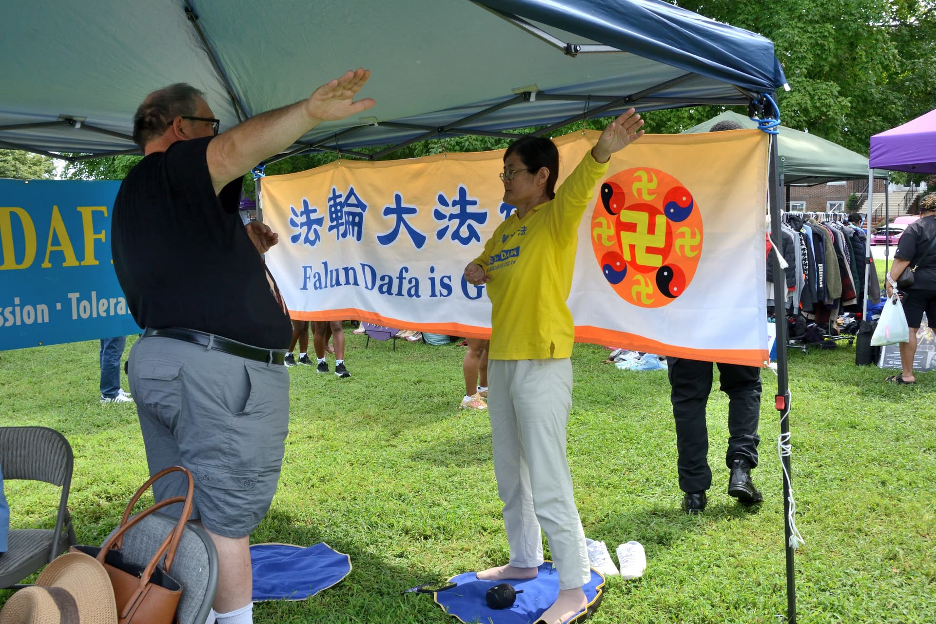 Paul Skivers (L), a school administrative assistant, learns Falun Gong exercises at the 4th annual Baila Con Dover Latin Festival in Dover, Del., on Aug. 29, 2026. (Frank Liang/The Epoch Times)