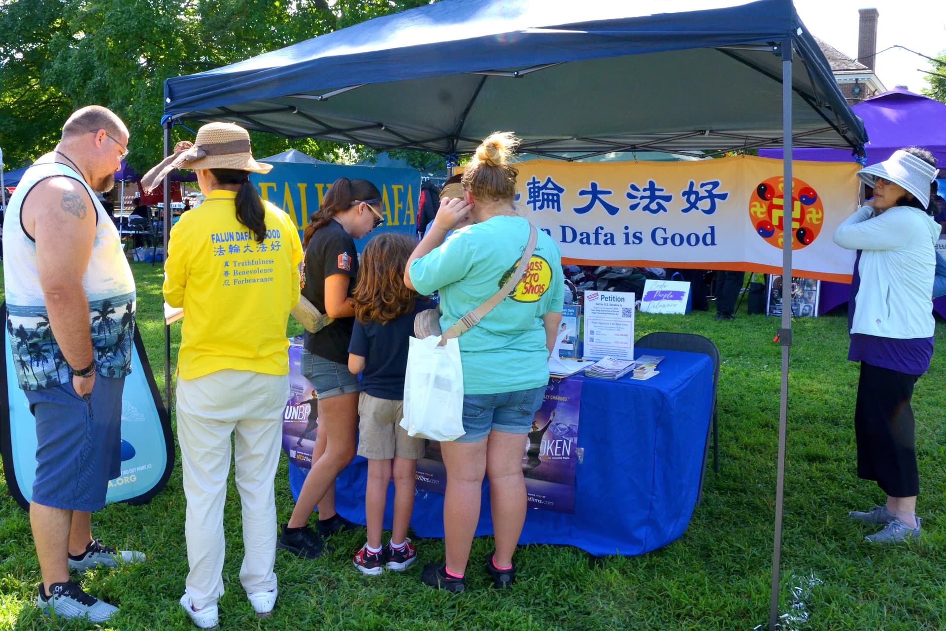 Eventgoers visit the Falun Gong booth to review Falun Gong information and sign a petition to support S.4009, the Falun Gong and Victims of Forced Organ Harvesting Protection Act, at the 4th annual Baila Con Dover Latin Festival on Aug. 29, 2026. (Frank Liang/The Epoch Times)