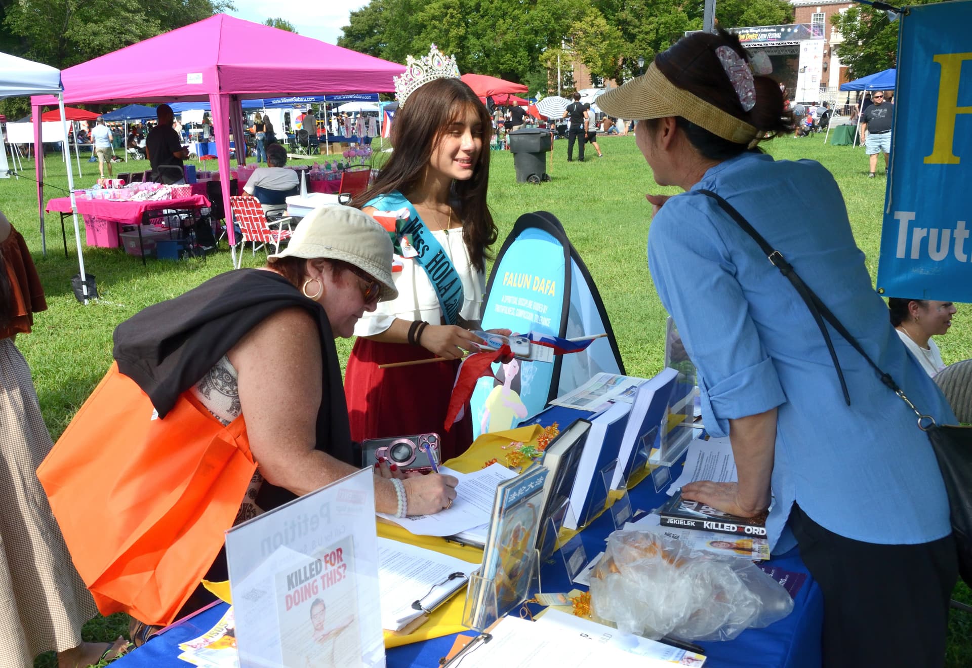 Eventgoers visit the Falun Gong booth to review Falun Gong information and sign a petition to support S.4009, the Falun Gong and Victims of Forced Organ Harvesting Protection Act, at the 4th annual Baila Con Dover Latin Festival on Aug. 29, 2026. (Frank Liang/The Epoch Times)