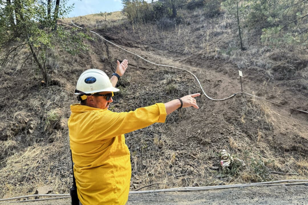Operations Section Chief Brett Pargman (L) points out the containment line that fire crews dug to make the fire turn the corner away from Mill Creek, in the Umatilla National Forest in northeast Oregon on Aug. 26, 2026. (T.J. Muscaro/The Epoch Times)