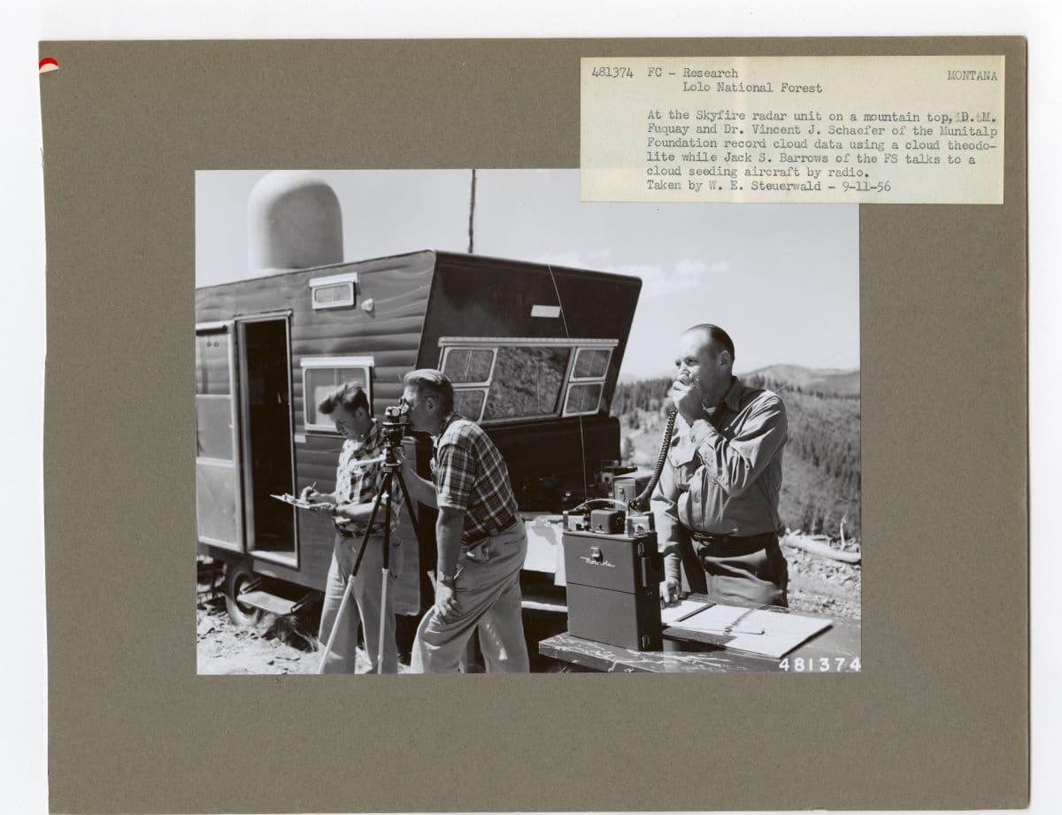 Donald Fuquay and Vincent J. Schaefer (C) record cloud data using a cloud theodolite, while Jack S. Barrows talks to a cloud seeding aircraft by radio. National Archives and Records Administration. (Public Domain)