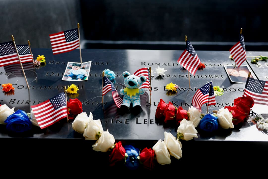 Flags, flowers, photographs, and a stuffed toy are placed on the inscribed names of victims in a reflecting pool at the 9/11 Memorial during a ceremony to commemorate the 25th anniversary of the Sept. 11, 2001, terror attacks on the World Trade Center at the National 9/11 Memorial and Museum in New York City on Sept. 11, 2026. (Jeenah Moon - Pool/Getty Images)