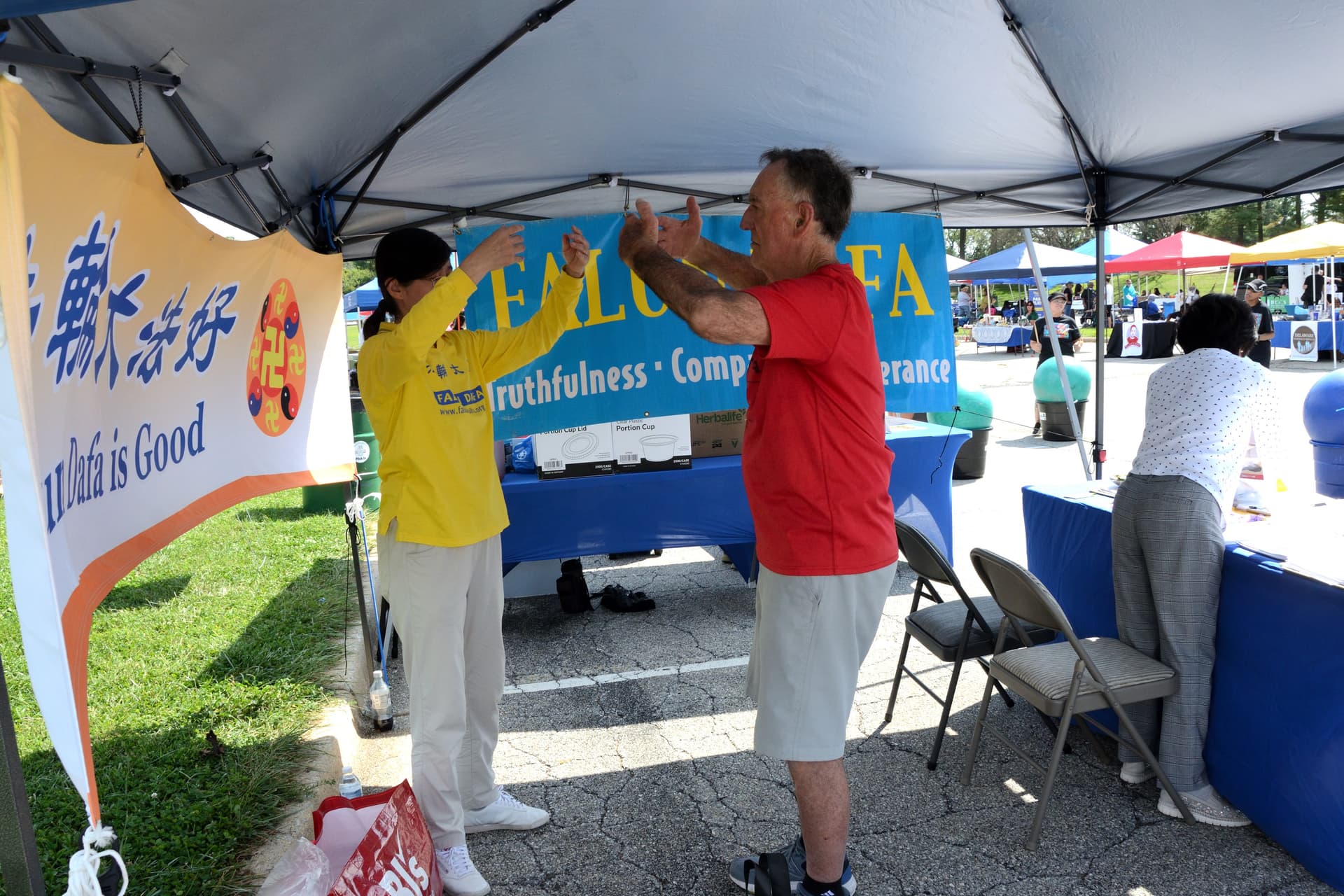 Joseph Jackson (R) learns Falun Gong exercises at Overdose Awareness Day Delaware on Sept. 12, 2026. (Frank Liang/The Epoch Times)