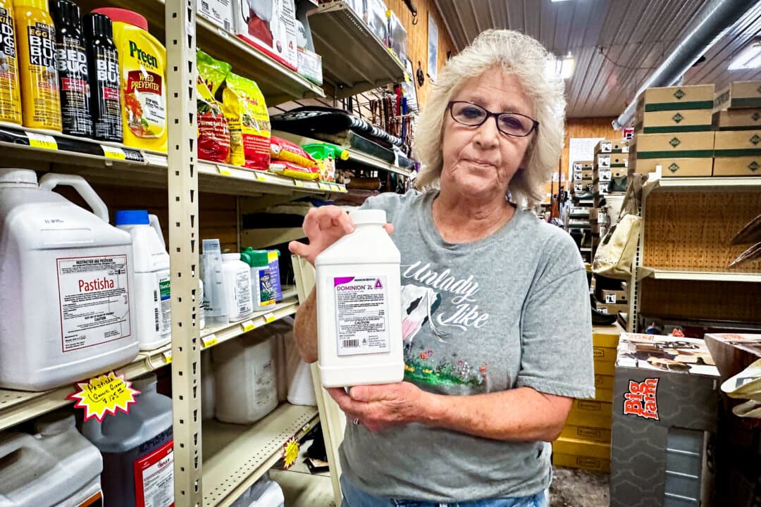 Kim Darnell, a longtime sales associate, holds up a product that customers use to treat their lawns for ticks, at Day and Day Feed Mill in Columbia, Ky., on Aug. 28, 2026. (Darlene McCormick Sanchez/The Epoch Times)