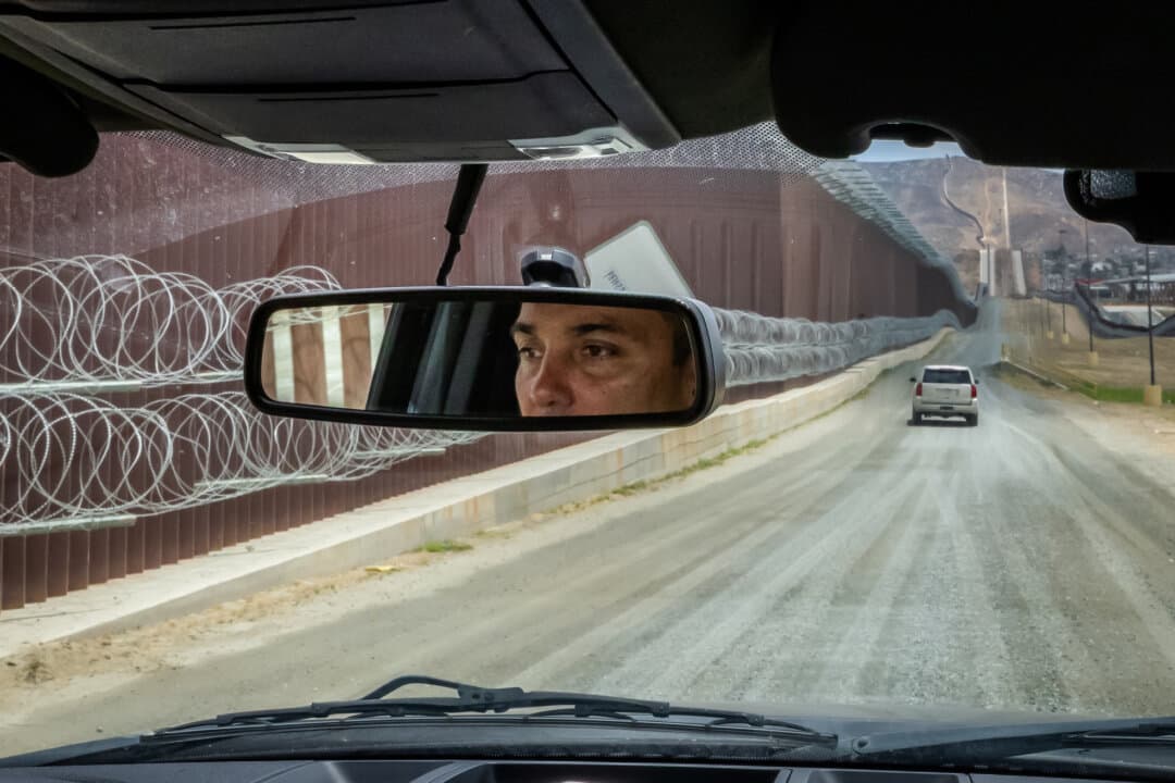 San Diego Border Patrol chief Justin De La Torre monitors the southern border wall outside San Diego on May 27, 2026. (John Fredricks/The Epoch Times)