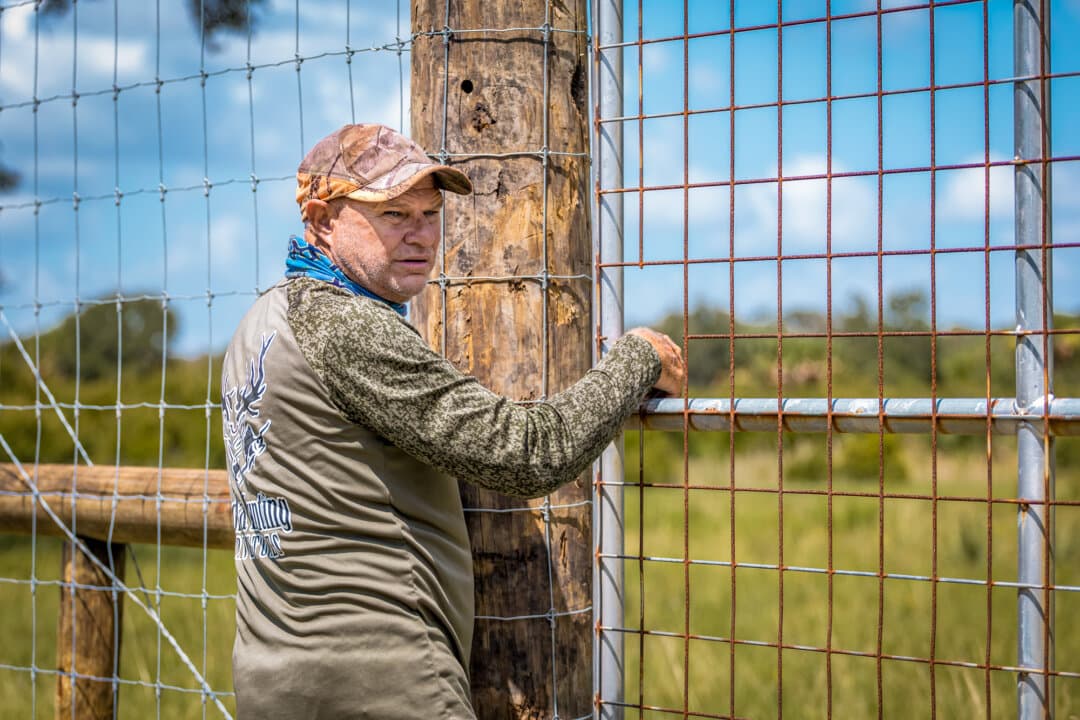 (Top) Ian Hall at the target practice stand, known as “Da Shootin Shak,” at Florida Hunting, Fishing, and Outdoor Adventures in Okeechobee, Fla., on July 24, 2026. (Bottom) Ian Hall opens a pasture gate in Okeechobee, Fla., on July 24, 2026. (Natasha Holt for The Epoch Times)