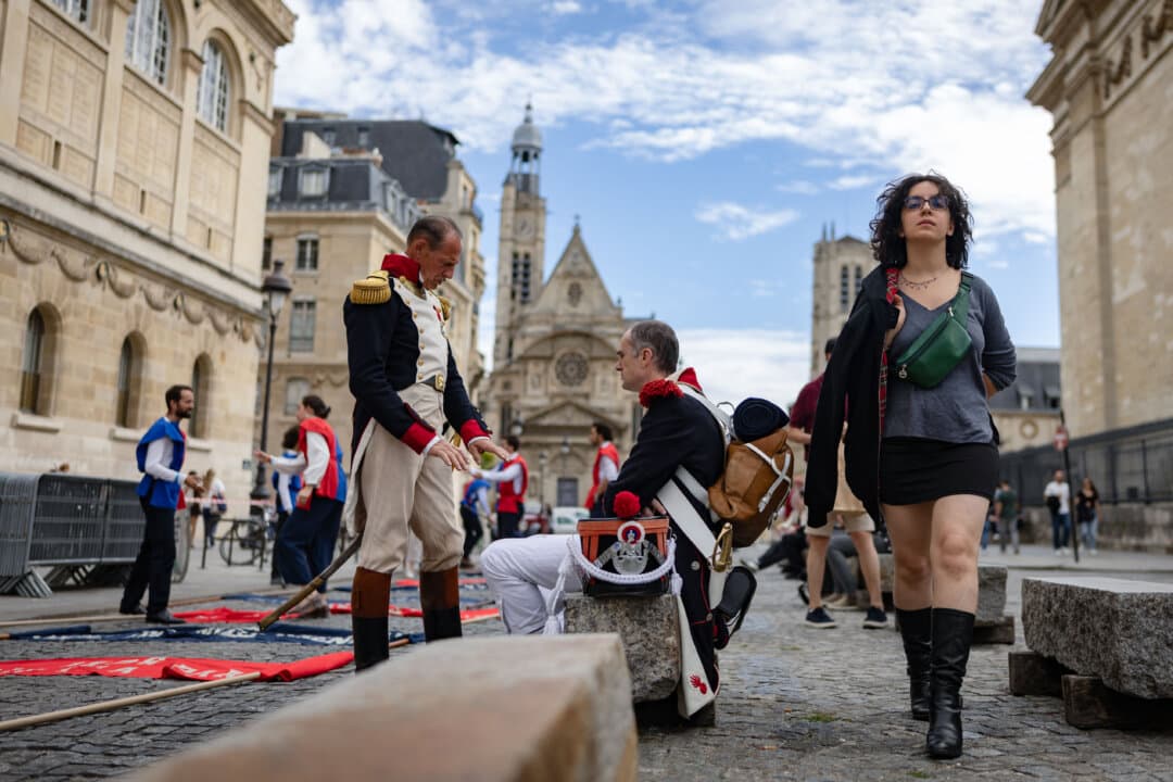 A pedestrian passes reenactors in Napoleonic military uniforms near the Saint-Etienne-du-Mont church and the Pantheon during the annual Fete de Paris parade in Paris on Sept. 13, 2026. (Ian Langsdon/AFP via Getty Images)