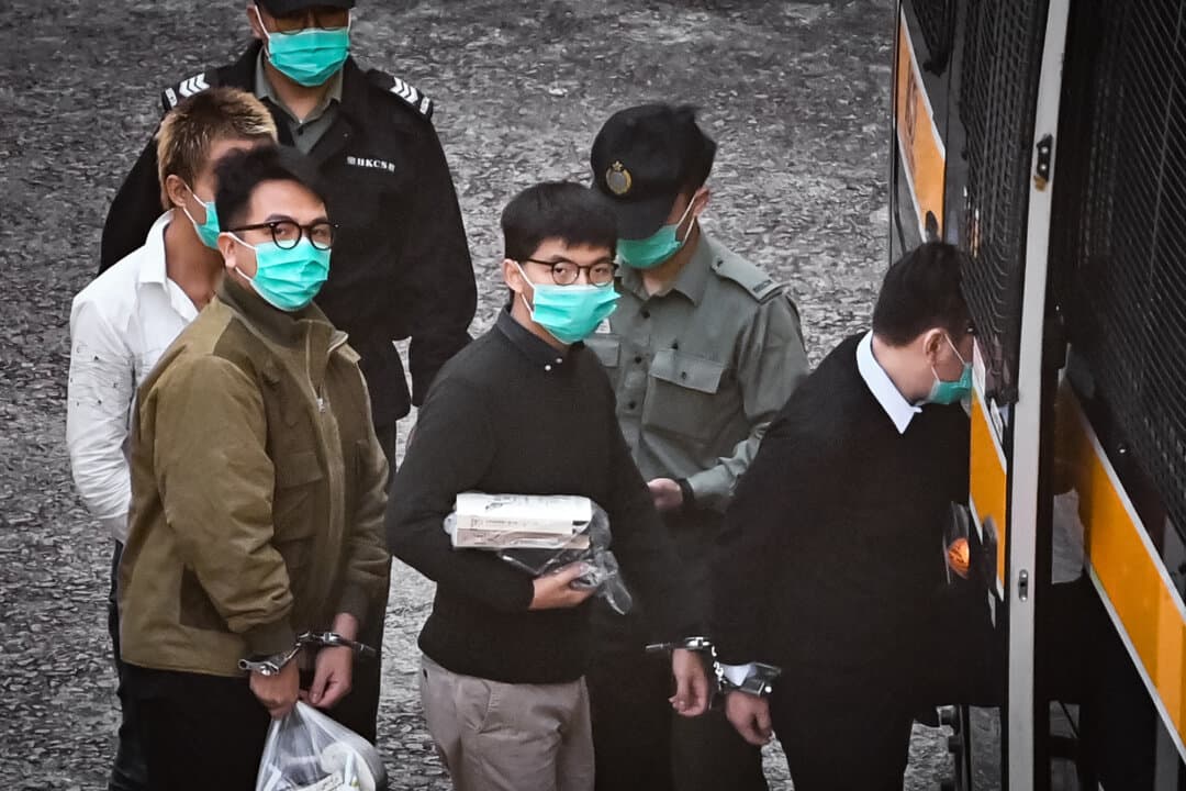Activists Joshua Wong (C) and Ivan Lam (R) board a police van before being taken to court to be sentenced over a 2019 protest that took place outside the city's police headquarters, at a maximum-security correctional facility in Hong Kong on Dec. 2, 2020. (Anthony Wallace/AFP via Getty Images)