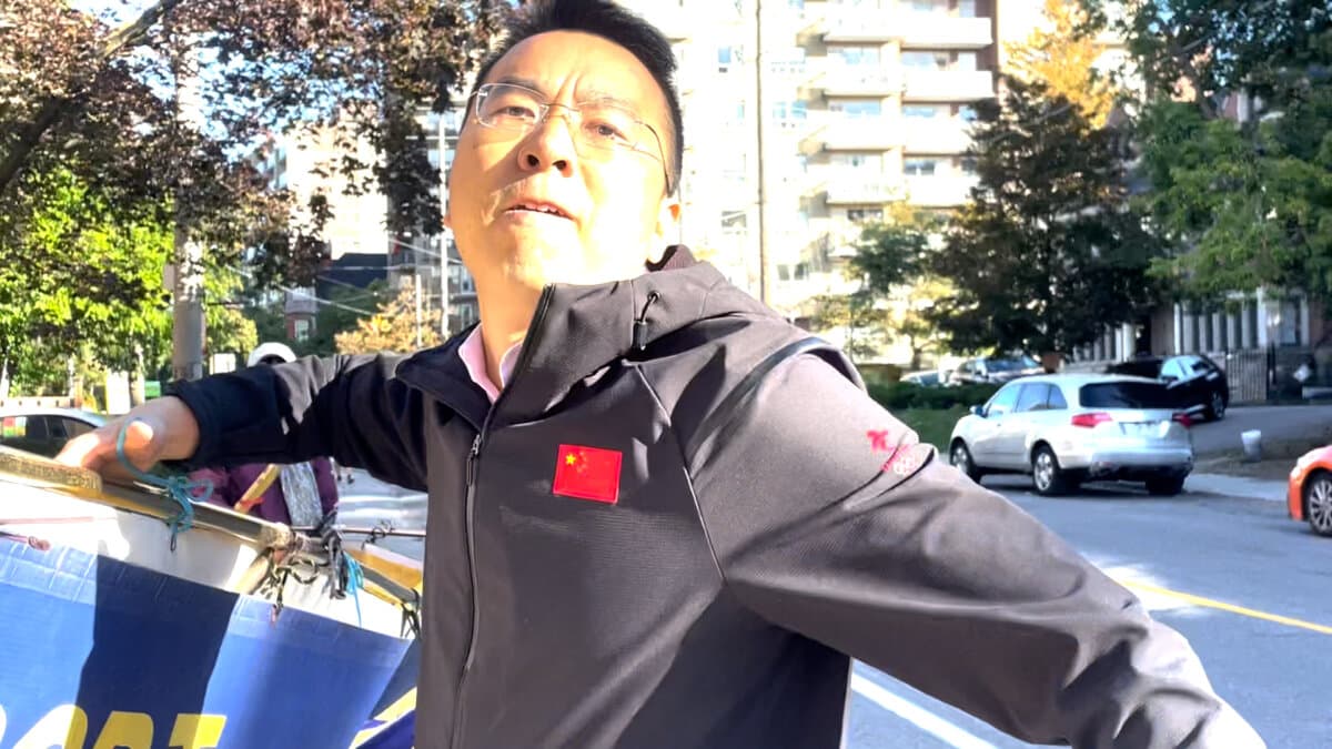 A man attacks a Falun Gong practitioner filming him as he forcefully removes their banners on a public sidewalk outside the Chinese Consulate in Toronto on Sept. 22, 2026. (Screenshot/Handout)