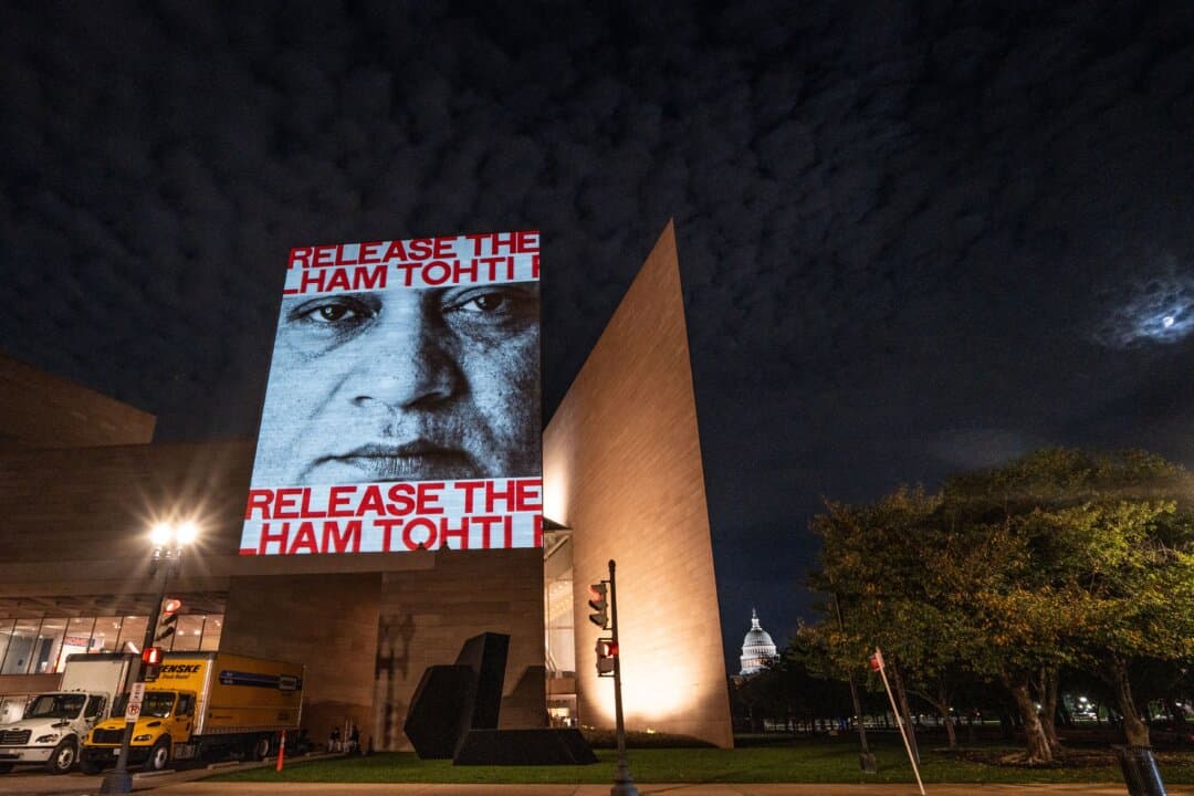 A projected photo of Ilham Tohti, an Uyghur scholar arbitrarily detained and held incommunicado since 2017, is displayed on the building of the National Gallery of Art as Chinese leader Xi Jinping visits Washington on Sept. 23, 2026. (Samira Bouaou/The Epoch Times)
