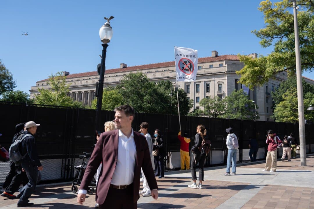 A pro-democracy activist holds up an anti-Chinese Communist Party (CCP) flag moments before he was confronted by CCP supporters, during Chinese leader Xi Jinping's arrival at the National Archives in Washington on Sept. 25, 2026. (Samira Bouaou/The Epoch Times)