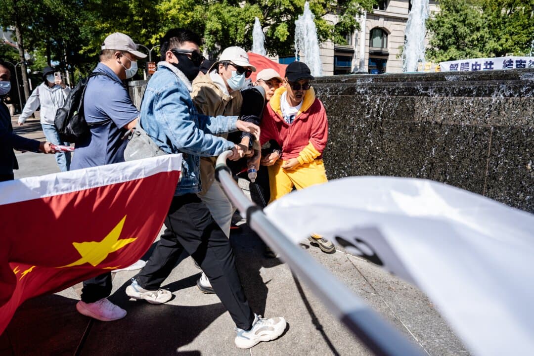 Chinese Communist Party supporters wrest a flag away from a pro-democracy activist around Chinese leader Xi Jinping's arrival at the National Archives in Washington on Sept. 25, 2026. (Samira Bouaou/The Epoch Times)