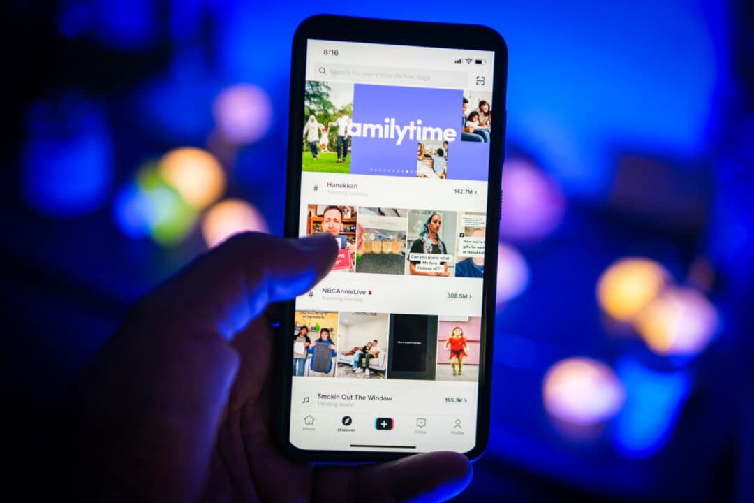 A man holds a phone displaying the TikTok app on Aug. 11, 2024, in this file photo. Apps such as TikTok or Instagram create a kind of “parasocial relationship” with influencers, says religion scholar Kelsey Hanson Woodruff, allowing followers to feel as if they're being engaged individually. (Oleksii Pydsosonnii/The Epoch Times)