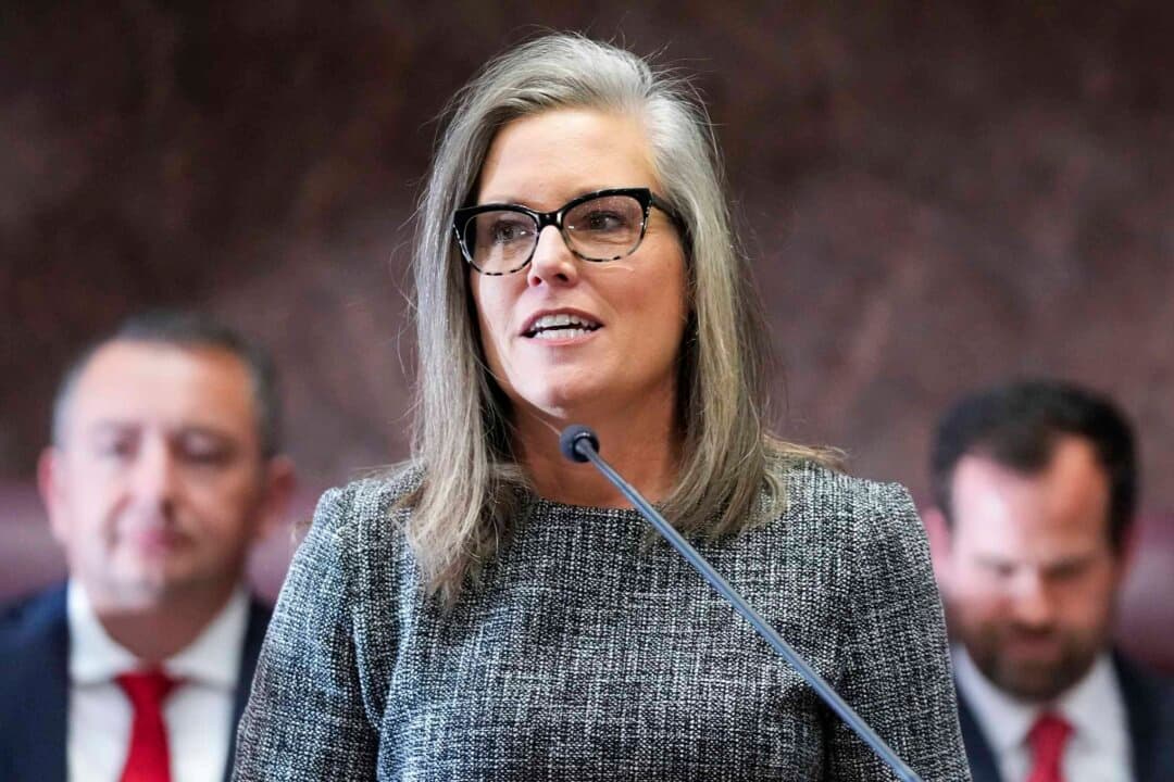 (Left) Arizona Gov. Katie Hobbs delivers the State of the State address at the Arizona state Capitol in Phoenix on Jan. 9, 2023. (Right) Rep. Andy Biggs (R-Ariz.), the Republican gubernatorial candidate, in Washington on Feb. 21, 2024. (Ross D. Franklin/AP Photo, Chip Somodevilla/Getty Images)