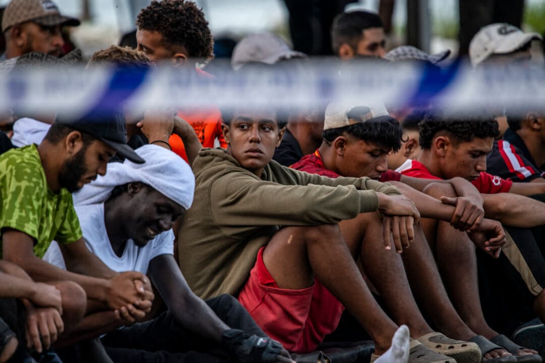 Migrants wait for food at a temporary camp near Trampolin beach in Spain’s North African enclave of Ceuta on Oct. 7, 2026. Hundreds remain in makeshift camps following a large influx of migrants from Morocco, fueling tensions in the enclave. (Antonio Sempere/AFP via Getty Images)