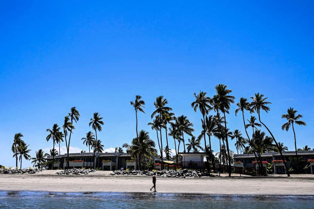 A tourist walks on the beach outside the Pacific Pre-COP31 Summit venue in Nadi, Fiji, on Oct. 7, 2026. Around 80 Pacific and Torres Strait community members, elders, and youth activists traveled in a flotilla carrying the message, “Keep 1.5°C Alive.” (Saeed Khan/AFP via Getty Images)
