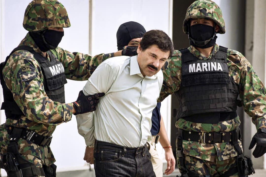 Mexican drug trafficker Joaquín Archivaldo Guzmán Loera, better known as “El Chapo” (C), is escorted by marines as he is presented to the press in Mexico City on Feb. 22, 2014. In 2015, El Chapo escaped from his maximum-security prison cell near Mexico City through an elaborate network fo tunnels.(Ronaldo Schemidt/AFP via Getty Images)