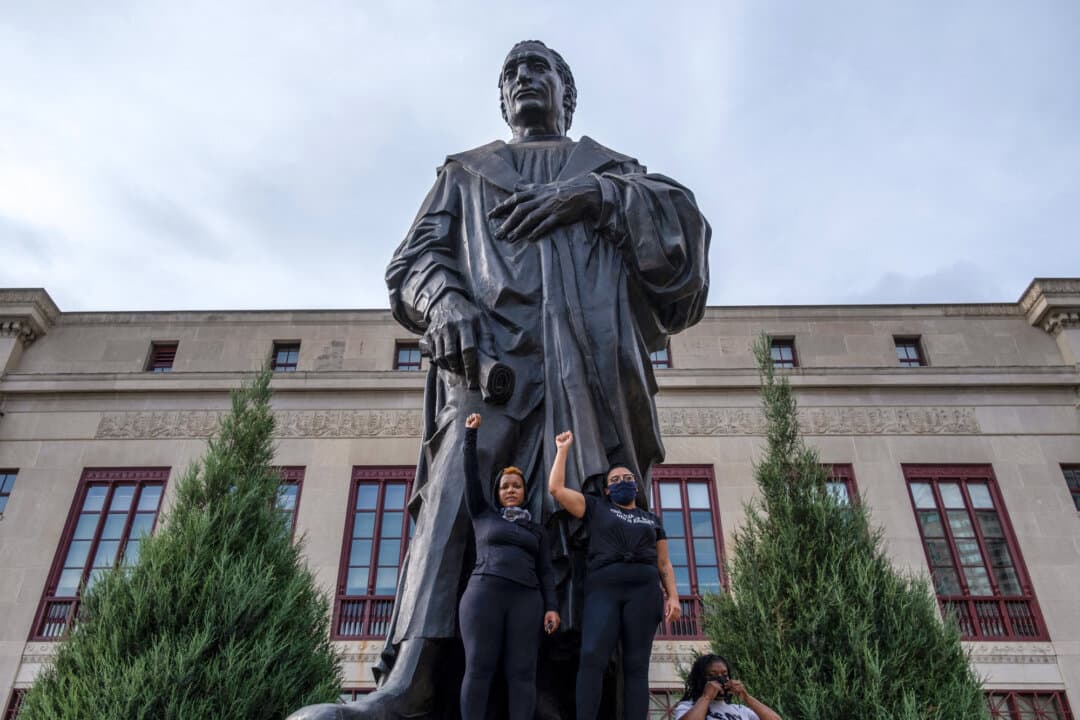 Protesters raise their fists as they stand at the base of a statue of Christopher Columbus in front of city hall in downtown Columbus, Ohio, on June 27, 2020, during an International March for Black Lives protest. (Seth Herald/AFP via Getty Images)