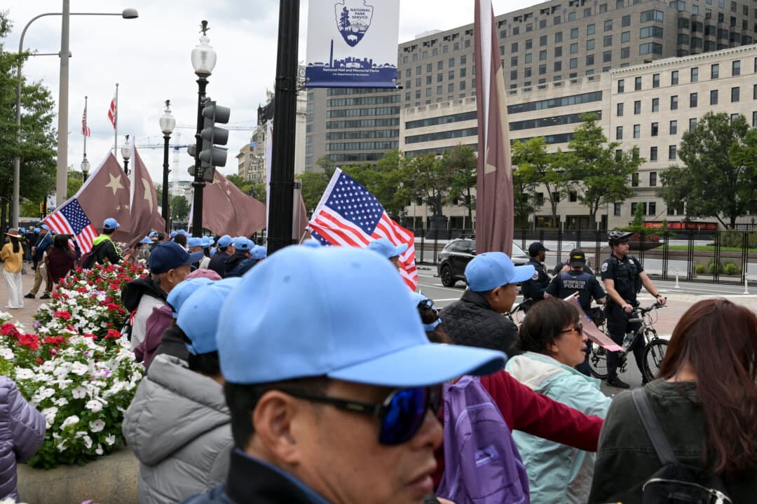 People holding Chinese and U.S. flags stand near police officers patrolling outside the Waldorf Astoria hotel as streets and sidewalks in the area are closed ahead of Chinese leader Xi Jinping's visit, in Washington on Sept. 23, 2026. (Oliver Contreras/AFP via Getty Images)