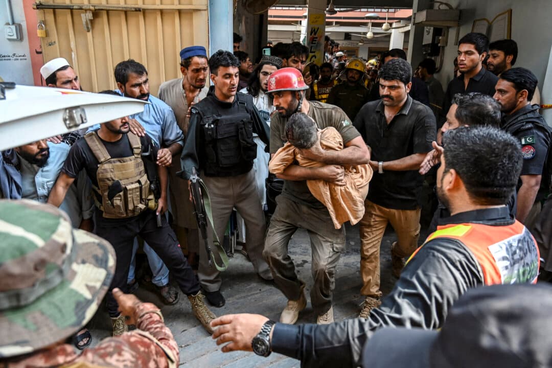 A rescuer carries a child during a search operation after a roof collapsed at a school in Peshawar, Pakistan, on Oct. 15, 2026. (Abdul Majeed/AFP via Getty Images)