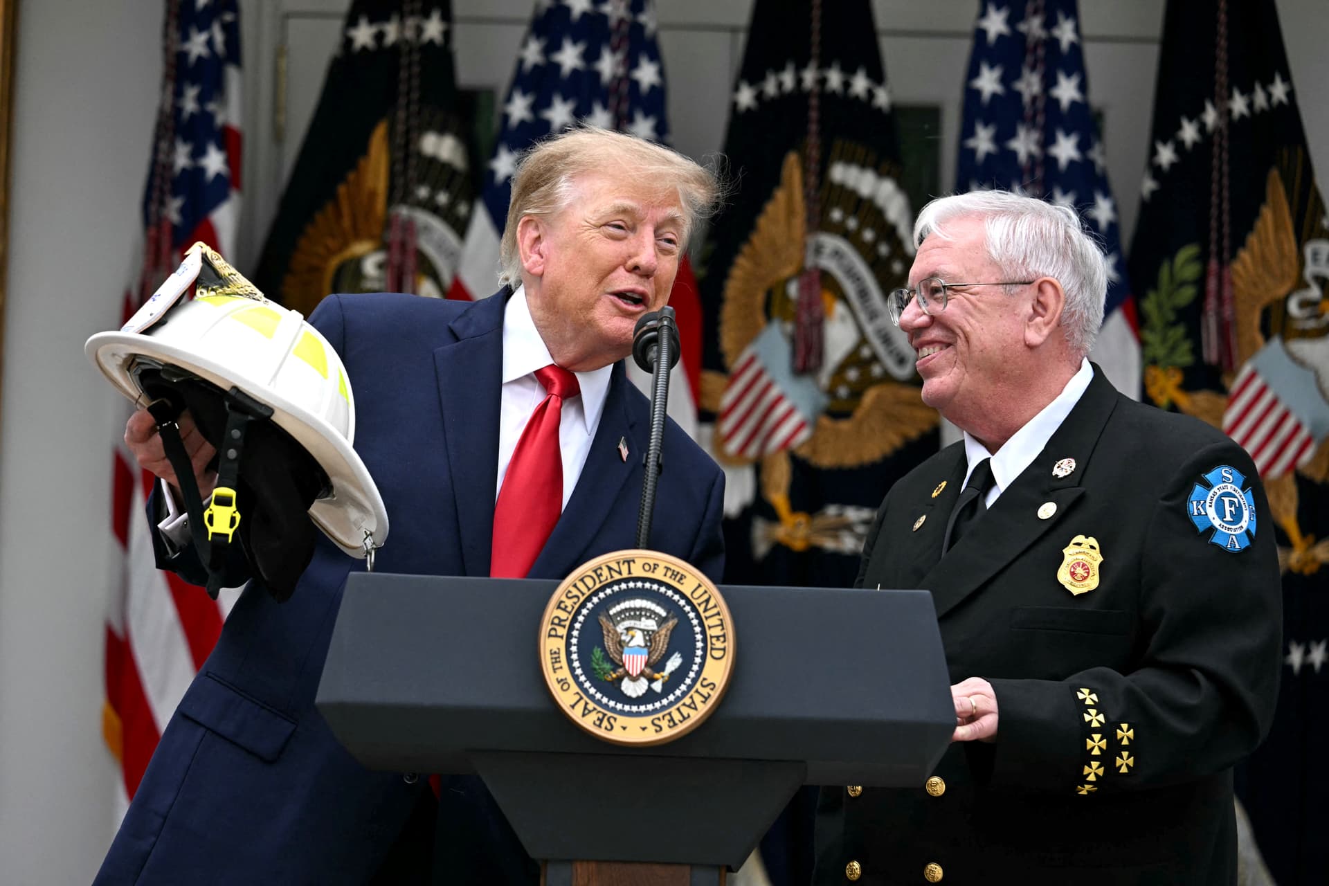 President Donald Trump (L) speaks whilst Steve Hirsch, chair of the National Volunteer Fire Council (NVFC) looks on in the Rose Garden at the White House, on Oct. 15, 2026. (Jim Watson/AFP via Getty Images)